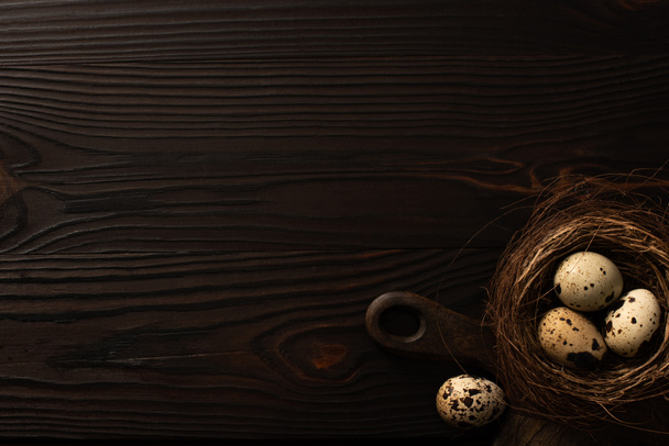 felső nézet fürj tojás barna fészek vágódeszka sötét fa felületen - Fotó, kép