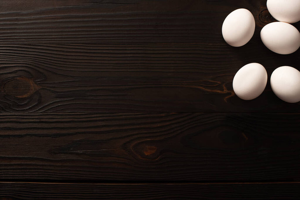 top view of white chicken eggs on dark wooden background - Foto, Imagen