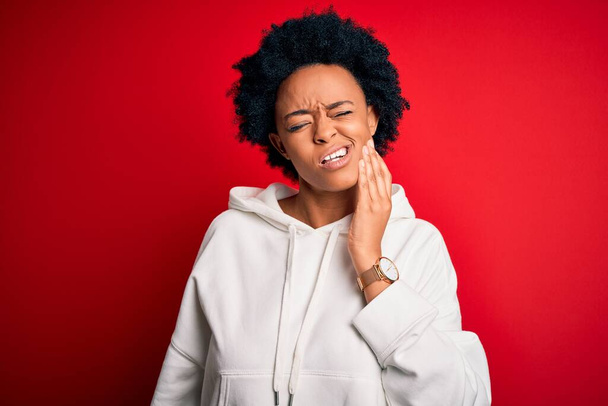 Young beautiful African American afro sportswoman with curly hair wearing sportswear touching mouth with hand with painful expression because of toothache or dental illness on teeth. Dentist - Фото, зображення