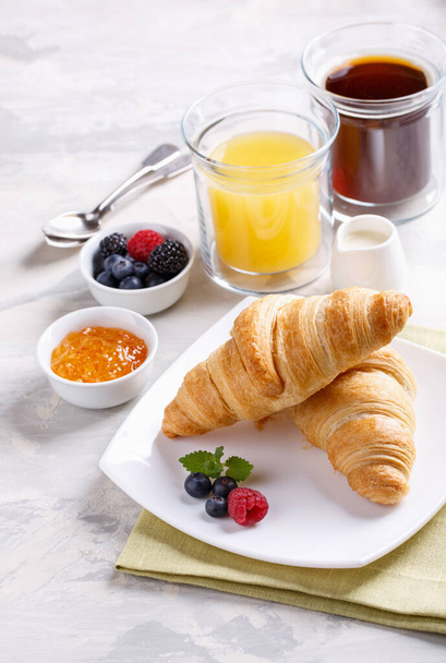 Ontbijt geserveerd met croissants, koffie, jus d'orange en bessen.  - Foto, afbeelding