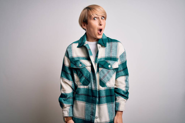 Young blonde woman with short hair wearing casual retro green shirt over isolated background afraid and shocked with surprise expression, fear and excited face. - Fotografie, Obrázek