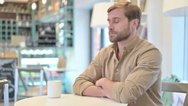 Zrelaksowany młodzieniec pijący kawę w kawiarni - Materiał filmowy, wideo