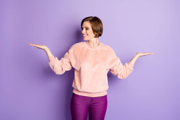 Portrait of cheerful positive girl hold hand select suggest option promo ads enjoy black friday offer wear pastel pullover isolated over violet color background - Foto, immagini