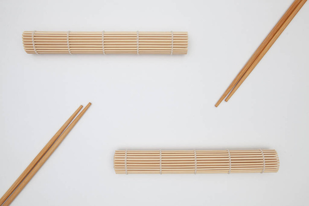 Bamboo mat with chopsticks for sushi on the white table. Food Design - Photo, image