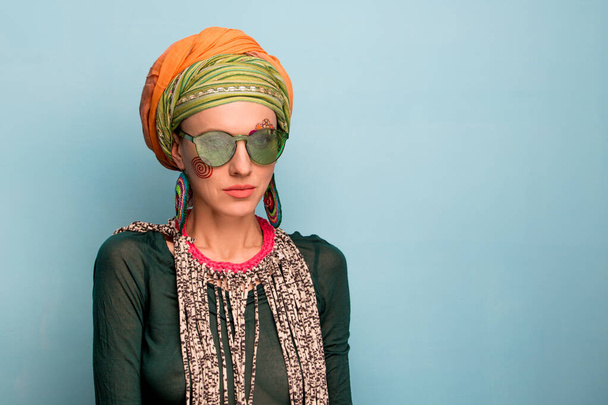 Beautiful woman with a turban on her head, fashion earrings and bracelets. Africa style woman concept - Foto, imagen