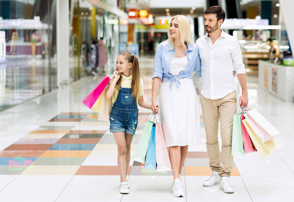 Οικογένεια για ψώνια στο εμπορικό κέντρο περπάτημα κρατώντας τα χέρια μεταφέρουν τσάντες - Φωτογραφία, εικόνα