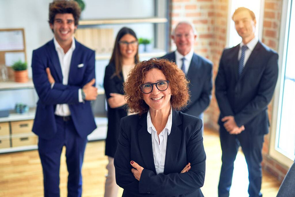 Egy csoport üzletember boldogan és magabiztosan mosolyog egy találkozón. Mosollyal az arcán állva a kamerába néz az irodában.. - Fotó, kép