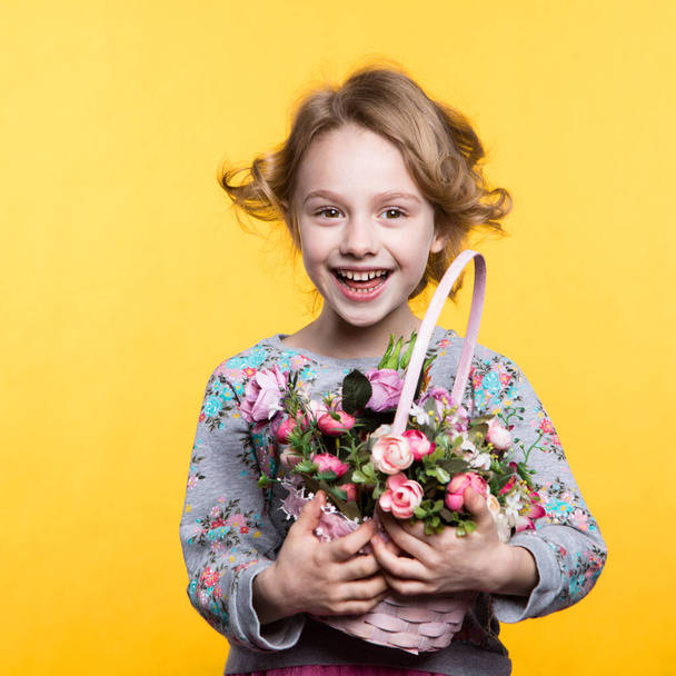 Little smile girl with flowers in basket. - Fotó, kép