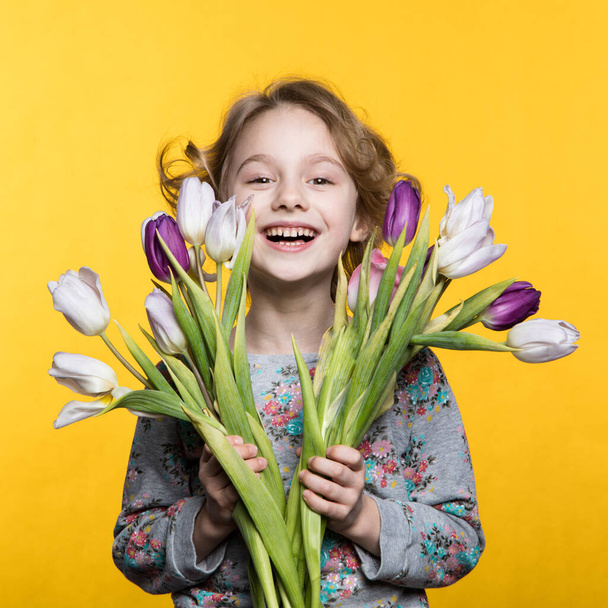 Little girl with a bouquet of tulips - Фото, изображение