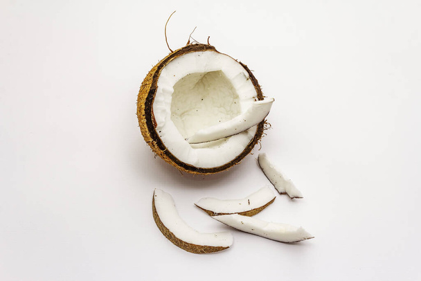 Ώριμη καρύδα κομμένη σε δύο μισά απομονωμένη σε λευκό φόντο. Φρέσκα φρούτα, συστατικά για το μαγείρεμα των τροφίμων ή την ομορφιά αυτο φροντίδα - Φωτογραφία, εικόνα