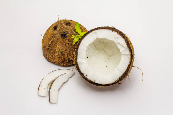 Érett kókusz vágás két félig elszigetelt fehér háttér. Friss gyümölcs, élelmiszer főzéséhez vagy szépségápoláshoz használt összetevő - Fotó, kép