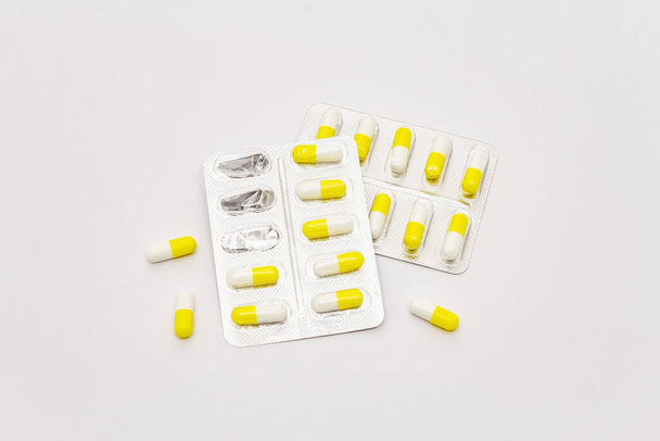 Farmaceutische tabletten, gele witte capsules in blisterverpakking geïsoleerd op witte achtergrond. Behandeling van diverse ziekten, traditionele geneeskunde - Foto, afbeelding
