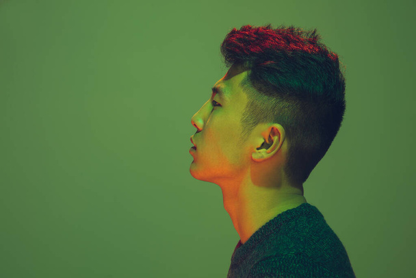 Portrait of a guy with colorful neon light on green background - cyberpunk concept - 写真・画像