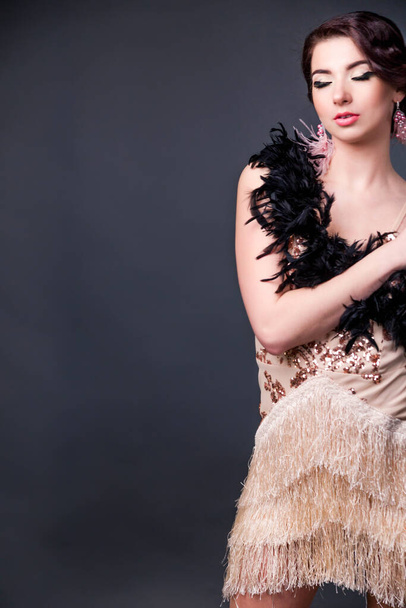 Morena sensual hermosa mujer en boa de plumas de avestruz sobre fondo negro. Verycal foto
 - Foto, Imagen