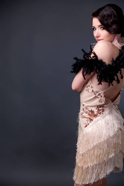 Sensual brunette beautiful woman in boa from ostrich feathers on black background. Verycal photo - Фото, зображення