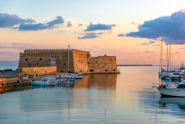 Antigua fortaleza de Koules en el puerto de Herkalion al atardecer. Hermosa vista con mar tranquilo, cielo colorido y yates
 - Foto, imagen