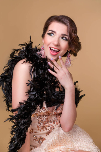 Brunette beautiful woman in boa from ostrich feathers sit on the chair and surprise. Vertycal photo - Valokuva, kuva