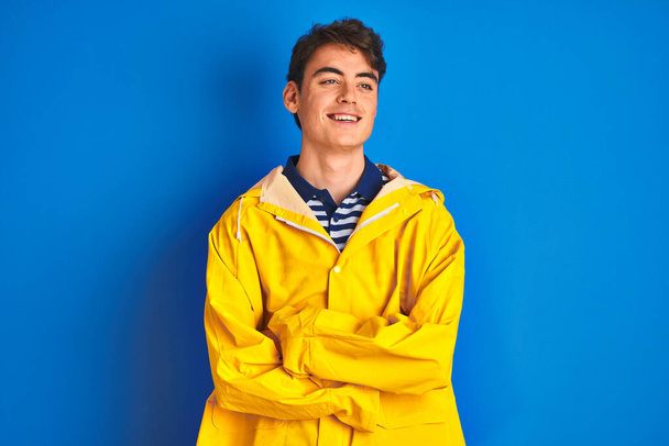 Teenager rybář chlapec na sobě žlutý plášť přes izolované pozadí s úsměvem na stranu a zírá pryč myšlení. - Fotografie, Obrázek