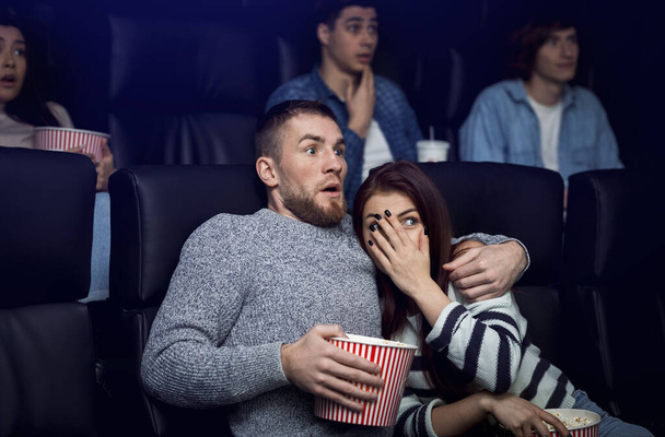 Movie date. Terrified couple watching scary film in cinema - Foto, afbeelding