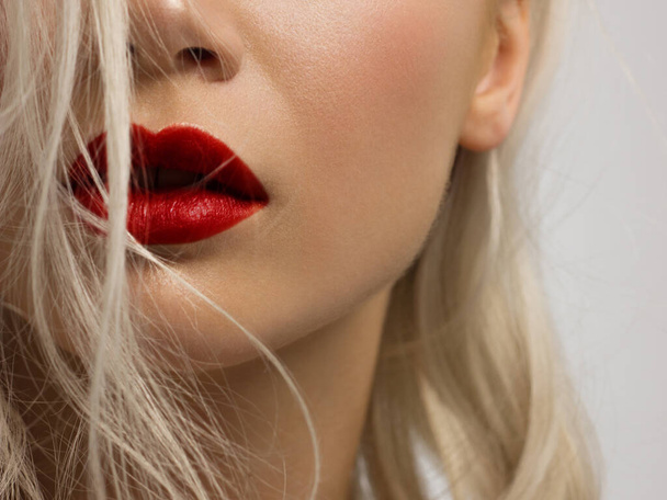 Sexual full lips. Red gloss of lips and woman's skin. The mouth is closed. Increase in lips, cosmetology. red lipstick. Open mouth and with teeth. blonde hair. - 写真・画像