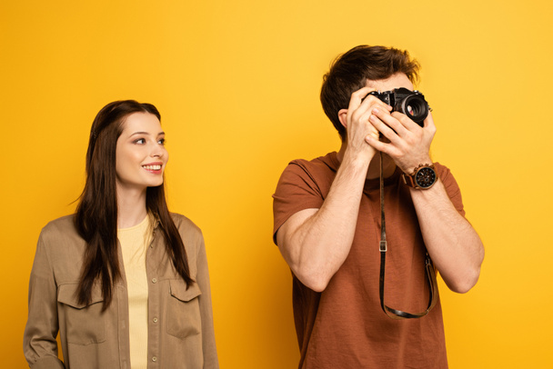 couple of happy tourists taking photo on photo camera on yellow - Foto, immagini