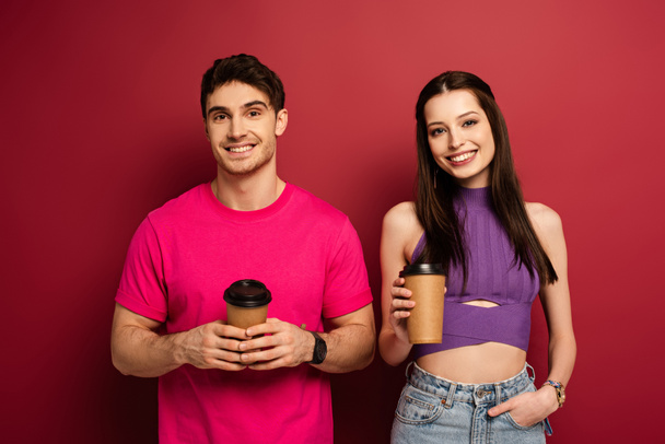 beautiful happy couple holding coffee to go on red - Photo, Image