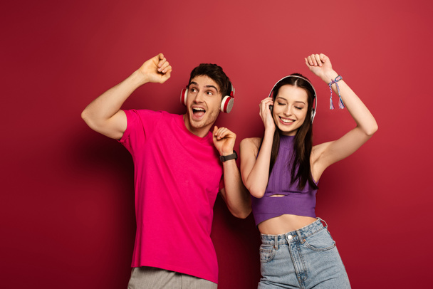 beautiful couple dancing and listening music with headphones on red - Foto, Imagem