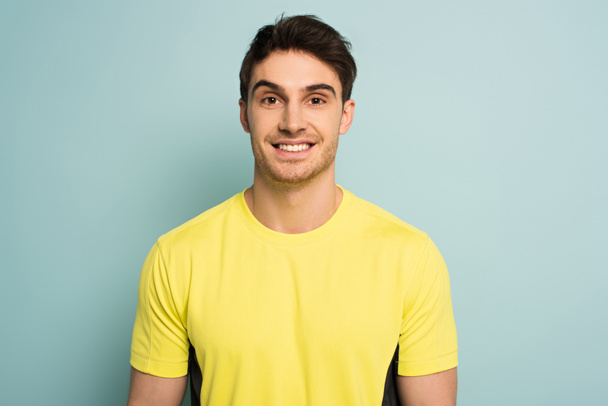 cheerful sportsman in yellow t-shirt on blue - Photo, Image
