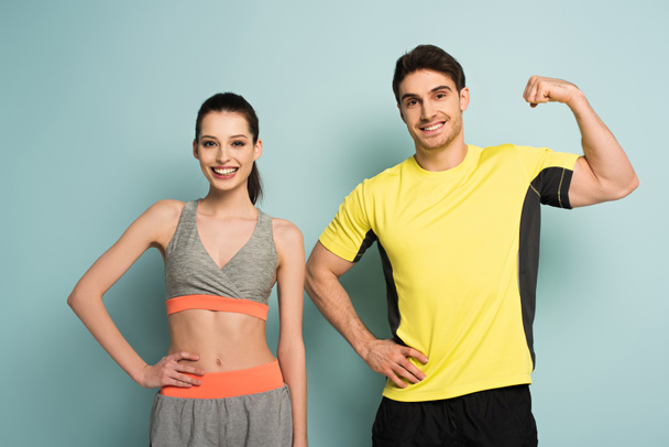 happy athletic couple standing in sportswear on blue - Photo, Image