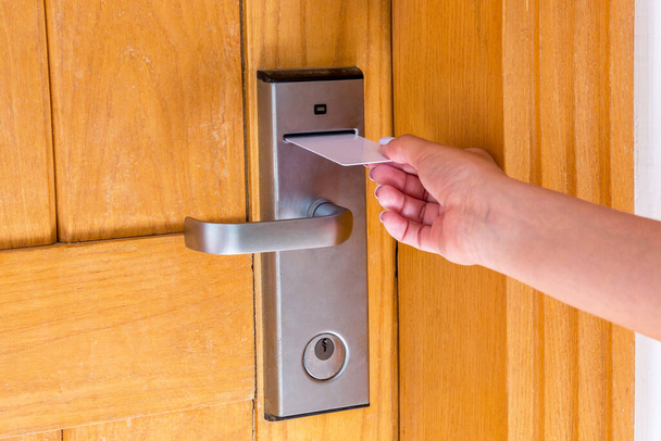 Female hand putting and holding magnetic key card switch in to open hotel room door. - Photo, Image