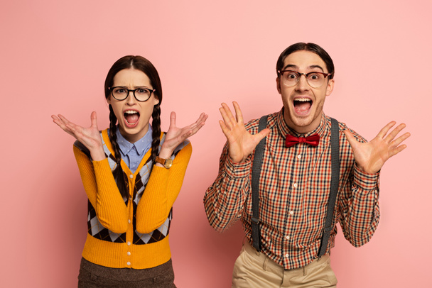 couple of shocked nerds in eyeglasses yelling on pink - Fotó, kép