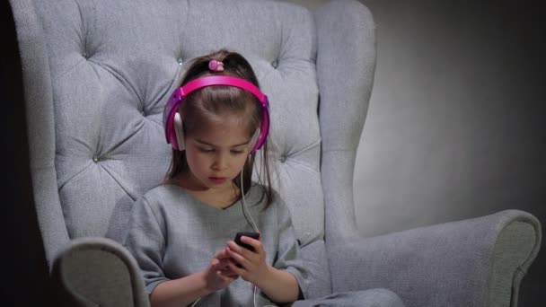 charming girl listens to music on chair - Filmmaterial, Video