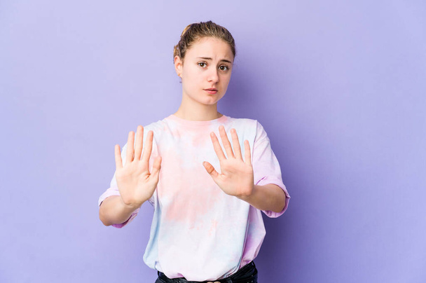 Молода біла жінка на фіолетовому фоні відкидає когось, хто показує жест огиди
. - Фото, зображення