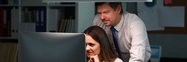 Женщина показывает мужчине в офисе информацию на мониторе
 - Фото, изображение
