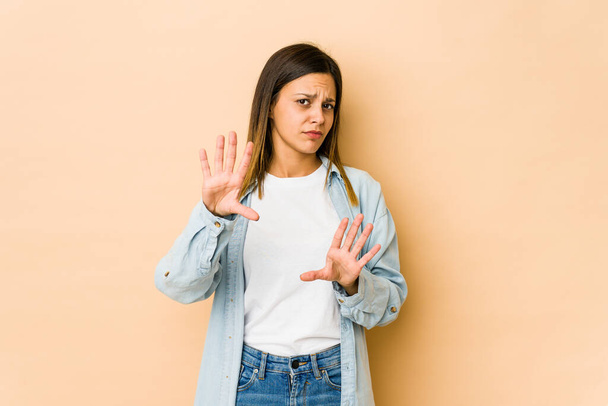 Young woman isolated on beige background rejecting someone showing a gesture of disgust. - Photo, Image