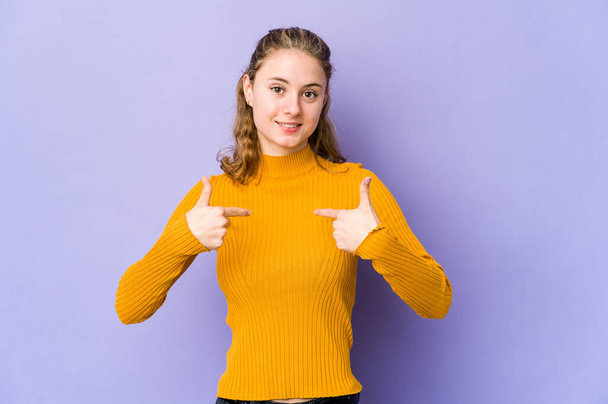 Young caucasian woman on purple background surprised pointing with finger, smiling broadly. - Photo, Image