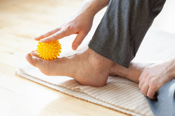 muž dělá ploché nohy korekce vlastní masáž s míčem doma - Fotografie, Obrázek
