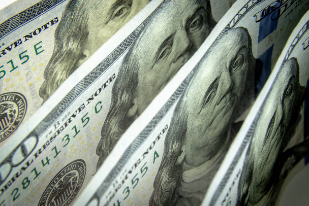Бенджамин Франклин смотрит из стопки банкнот в 100 долларов США. Концепция валютных курсов. Американская смородина как концепция мировых денег
. - Фото, изображение