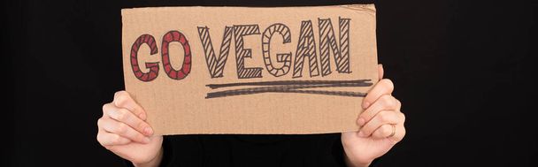Panoramaaufnahme einer Frau mit Pappschild mit veganer Aufschrift isoliert auf schwarz - Foto, Bild