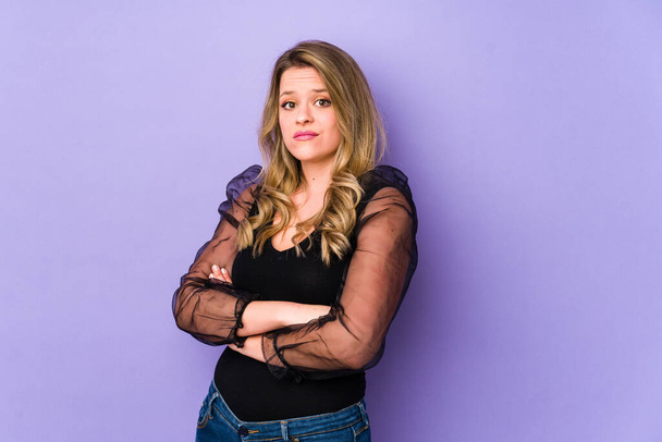 Young caucasian woman isolated on purple background suspicious, uncertain, examining you. - Photo, image