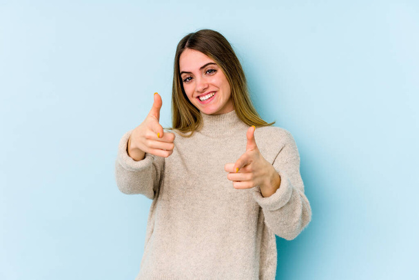 Молода біла жінка ізольована на синьому фоні веселі посмішки, що вказують на передній план
. - Фото, зображення