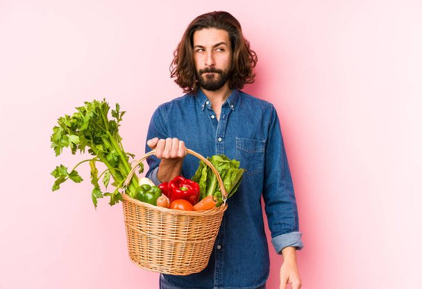 Jeune homme cueillant des légumes biologiques dans son jardin isolé confus, se sent douteux et incertain
. - Photo, image