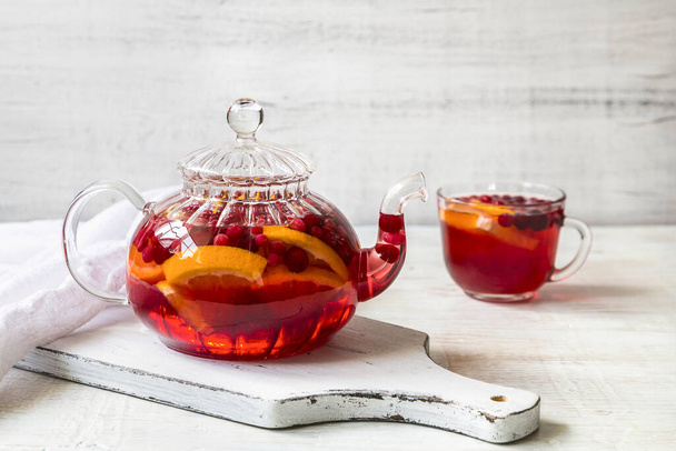 Chá de frutas com laranja, cranberries, cranberries e especiarias em um fundo leve
. - Foto, Imagem