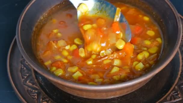 Sopa de tomate rojo hervido solo caliente con maíz, que se mezcla con una cuchara en un plato de arcilla marrón en un estilo rústico
 - Metraje, vídeo