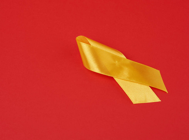 żółta wstążka jedwabna na czerwonym tle. Świadomość raka kości mięsaka, przestrzeń kopiująca - Zdjęcie, obraz