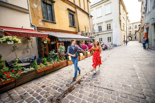 a young couple is stylishly dressed, a girl in a red dress, a man in a blue shirt and blue pants, walk the streets in Krakow Poland - Foto, Imagen
