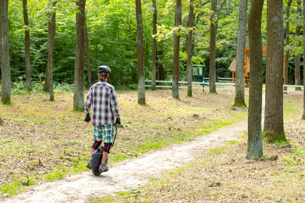 Hipster in beschermende kleding rijden een evenwicht een wiel elektrische scooter in het natuurreservaat. - Foto, afbeelding