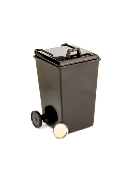 Batería de la tableta delante de la cesta de basura de juguete negro. Reciclaje de residuos electrónicos. Concepto ecológico
. - Foto, imagen