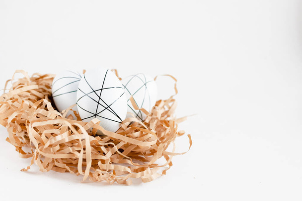 Oeufs décorés d'or de Pâques dans le nid sur fond blanc. Espace minimal de copie de concept de Pâques pour le texte. Vue du dessus, flatlay
. - Photo, image