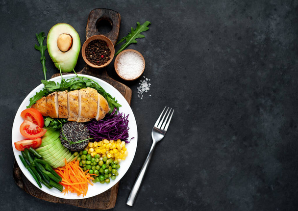 gegrilde kipfilet met groenten en kruiden op een donkere achtergrond, bovenaanzicht. Avocado, chia, maïs en sperziebonen - Foto, afbeelding